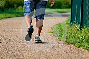 Man walking with sneakers on a path, close-up of his legs, sports activity, healthy lifetsyle