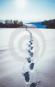 man walking in snow footprints