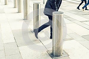 Man walking by stainless steel bollard entering pedestrian area on Vienna city street. Car and vehicle traffic access control