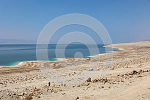 Man walking among stones to dead sea shore