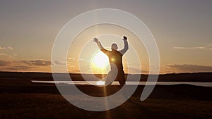 Man walking on summer meadow, sunset. Silhouette of the young man on the mountain top.