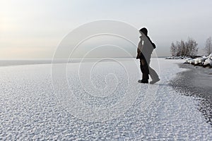 Man walking on a thin ice of a freezing pond at sunset