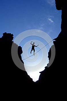 Man walking on tight rope over the rock photo