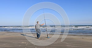 Man walking to fishing pole beach surf fishing Texas ocean 4K