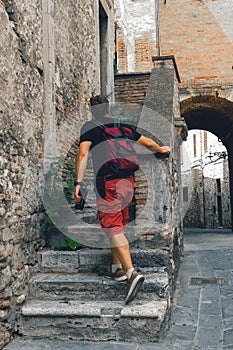 Man walking. Tourist. Narni Terni, Umbria, Italy, medieval city: a typical old street. Vertical photo. in action