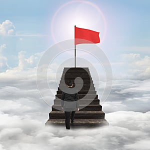 Man walking toward red wavy flag on top of stairs