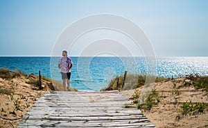 Man walking towards the beach on a wooden path at holidays