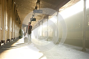 Man walking at train station calling by mobile phone