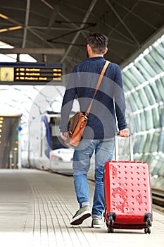 Man walking on train station platform with travel bag