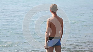 Man walking into warm sea, opening hands wide to embrace its boundless breadth