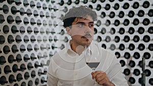 Man walking wine cellar holding goblet grape drink close up. Sommelier sniffing.