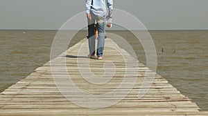 Man Walking on Wooden Dock Toward the Sea