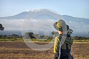 man walks against backdrop of Kilimanjaro. African walking safari. male traveler with backpack looking at amazing