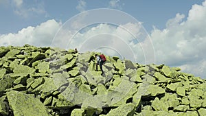 A man walks along a mountain slope covered with giant stones. Solo tourism.