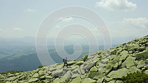 A man walks along a mountain slope covered with giant stones. Solo tourism.