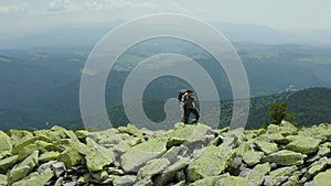 A man walks along a mountain slope covered with giant stones. Solo tourism.