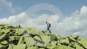A man walks along a mountain slope covered with giant stones. Solo tourism.