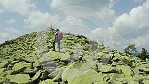 A man walks along a mountain slope covered with giant stones. Solo tourism.