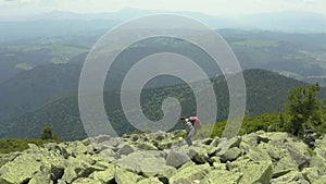 A man walks along a mountain slope covered with giant stones. Solo tourism.