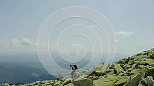 A man walks along a mountain slope covered with giant stones. Solo tourism.