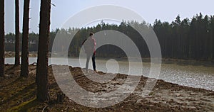 A man walks along a path in a park near a lake in the early morning in the autumn. Man Hill Top. Young Man Standing On