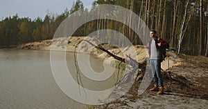 A man walks along a path in a park near a lake in the early morning in the autumn. Man Hill Top. Young Man Standing On