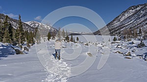 A man walks along a path trodden in the snow.