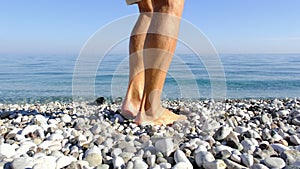 Man walks along pebble beach does feet massage. Acupuncture healthy lifestyle.