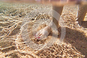 A man walks along the sea beach along the coastline and touches the sandy bottom with his feet