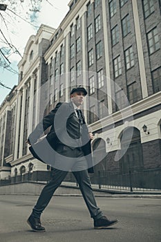 A man walks at city street in the image of an English retro gangster in Peaky blinders style