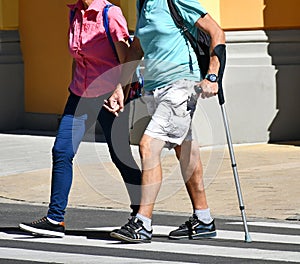 Man walks with a crutch on the street