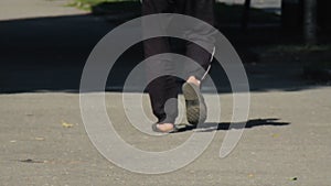 A man walks down street in black sweatpants and flip-flops.