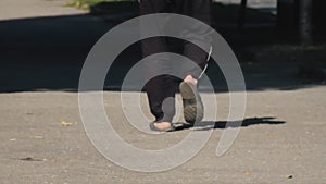 A man walks down the street in black sweatpants and flip-flops on his bare feet. Summer warm day. Sunlight. Casual clothes. No fac