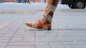 A man walks down the street with a long, confident stride. Close-up steps