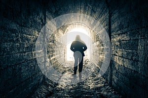 The man walks down the tunnel towards the light