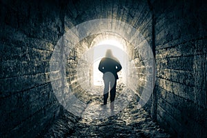 The man walks down the tunnel towards the light photo