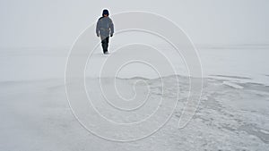 A man walks on a frozen surface of a lake