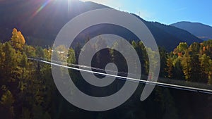 Man walks on hanging rope river bridge in forest