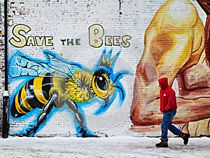 Man walks past a Save the Bees wall mural