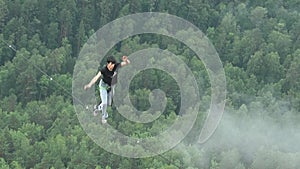 A man walks on a rope stretched at an altitude between two peaks in the Siberian nature reserve Stolby.