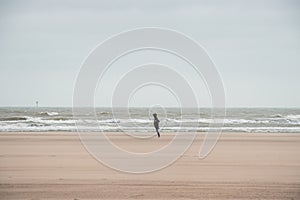 Man walks on a sandy beach in the face of high winds near Blankenberge, west coast of Belgium. Exploring and discovering Belgium