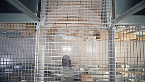 Man walks on stairs in warehouse. Creative. Close-up of man walking along mesh path over warehouse. High shelves with