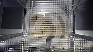 Man walks on stairs in warehouse. Creative. Close-up of man walking along mesh path over warehouse. High shelves with