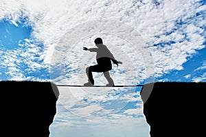 Man walks on a tightrope over a cliff