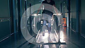 A man walks on a track, using robotic orthopaedic device at a clinic. 4K