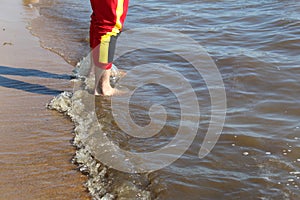 A man walks on the water along the shore with bare feet