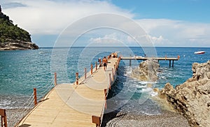 A man walks on a wooden pier to swim in the sea.