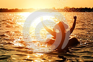 A man ware hat and he is on swim tube in the water. He is hands up to make water splash.