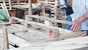Man in a ware house using a nail gun for wooden pallets