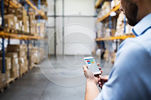 Man warehouse worker with a smartphone.